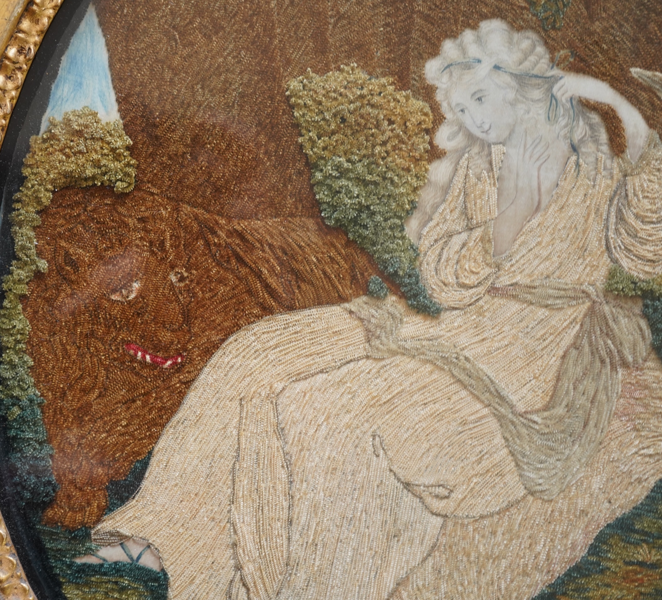 A pair of unusual early 19th century oval silk Chenille embroideries, one depicting a seated lady surrounded by a lion and donkey, the other depicting a seated shepherdess under tree with two sheep. Both have water colou